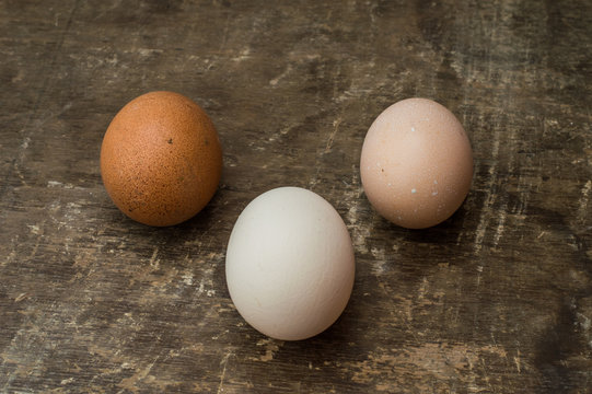 Three fresh chicken eggs on an old wooden background