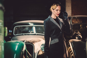 Naklejka na ściany i meble Woman among retro cars in garage