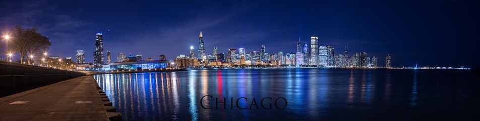 Obraz premium Chicago city downtown night panorama urban skyline with skyscrapers over Lake Michigan with clear blue sky.