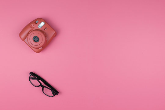 Camera and glasses on a pink background. Concept Fashion. Top view, flat lay.