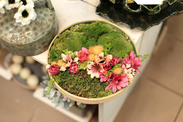 Stroik, dekoracja z kwiatów i mchu w drewnianym talerzu.