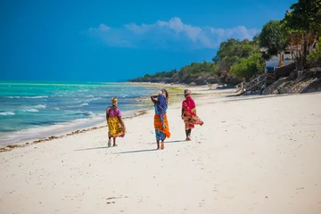  Drie vrouwen die op het strand in Jambiani, het eiland van Zanzibar, Tanzania lopen © margo1778