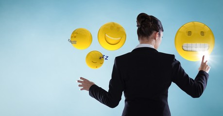 Back of business woman touching emojis against blue background