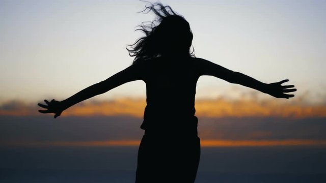 Young woman silhouette dancing after sunset