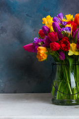 bouquet of bright spring flowers in vase on dark background