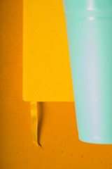 Yellow notepad and plastic turquoise glass on a yellow background
