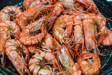 Giant tiger shrimps with heads fried in oil in a frying pan on a gas stove