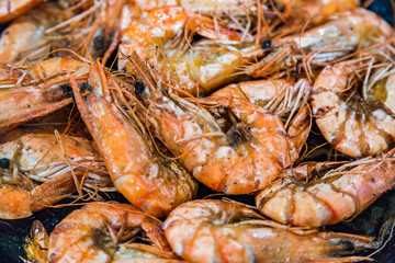 Giant tiger shrimps with heads fried in oil in a frying pan on a gas stove