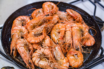 Giant tiger shrimps with heads fried in oil in a frying pan on a gas stove