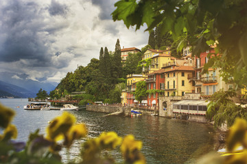 Beautiful cityscape with a Como lake coastline of italian Varenna city with colorful building, big trees, and dramatic sky