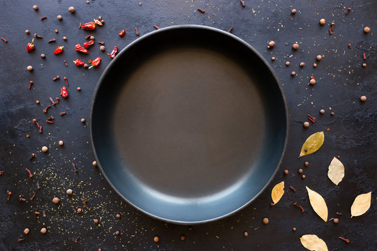 Empty frying pan and spices on a black background