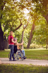 family time- senior man in wheelchair and daughter in the park.