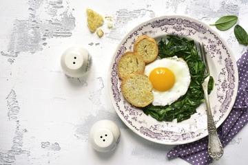Concept of healthy breakfast:spinach,fried organic egg and croutons.Top view with copy space.