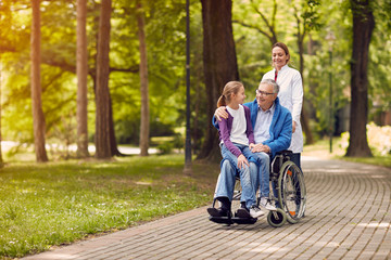 nurse pushing senior man on wheelchair with his granddaughter.