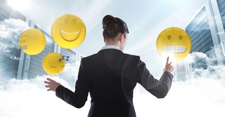 Back of woman touching emojis against sky and servers