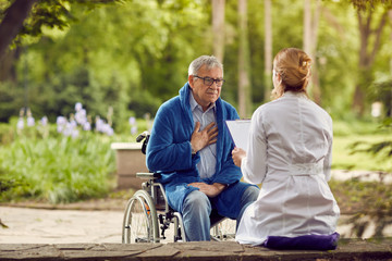 Nurse with elderly man in wheelchair who don't feel good. - obrazy, fototapety, plakaty