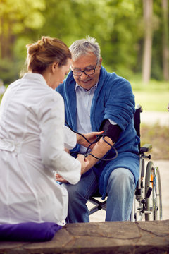 Nurse Assessment Of Blood Pressure Elderly Man In Wheelchair.