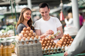smiling couple choosing eggs at the market.