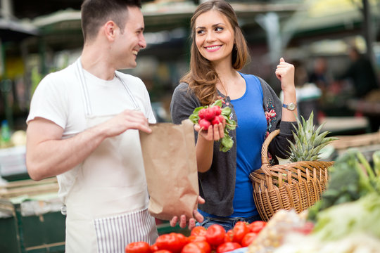 woman smiling and holding radishes at market.