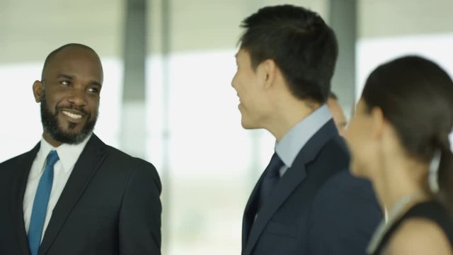  Cheerful business group chatting as they walk through busy modern office