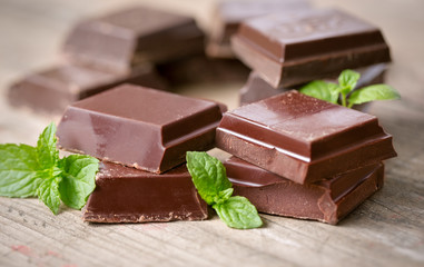 Stack of chocolate pieces with a leaf of mint.