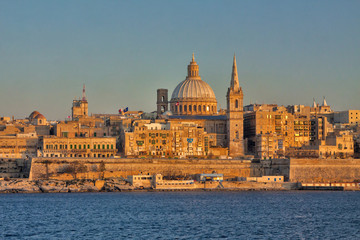 Fototapeta na wymiar Malta - Valetta - Valetta's cityscape at dusk with harbor waterfront and Our Lady of Mount Carmel catholic church. Taken from Sliema