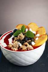 breakfast smoothie bowl with blueberries, peach and granola