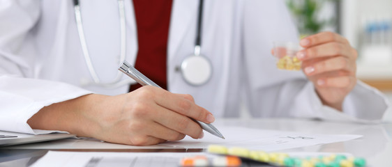 Female medicine doctor fills up  prescription form to patient closeup. Panacea and life save, prescribe treatment, legal drug store, contraception concept