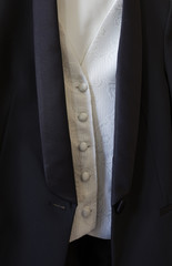 Traje negro sobre chaleco blanco con botones forrados de tela