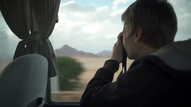Man taking photo of a mountain far away from the bus slow motion