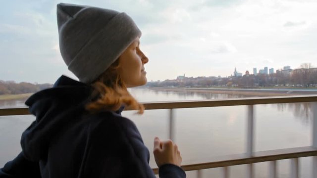 Slow Motion Outdoors jogging. Young Woman Running on Bridge over a River at the background of Beautiful City.