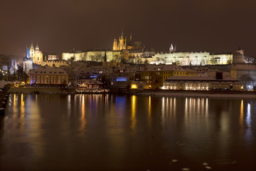 Night snowy Prague Lesser Town with gothic Castle above River Vltave, Czech republic