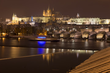 Fototapeta na wymiar Night snowy Prague Lesser Town with gothic Castle, St. Nicholas' Cathedral and Charles Bridge, Czech republic