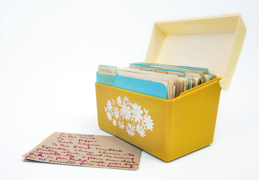 Front View Of Vintage 1970s Yellow Recipe Box With Recipe Card In Foreground. Isolated.