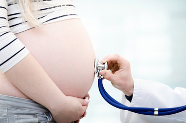 Doctor using stethoscope examining pregnant woman