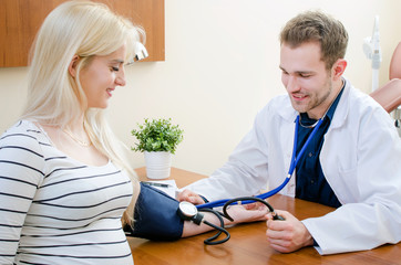 Obraz premium Young doctor checking blood pressure of female patient