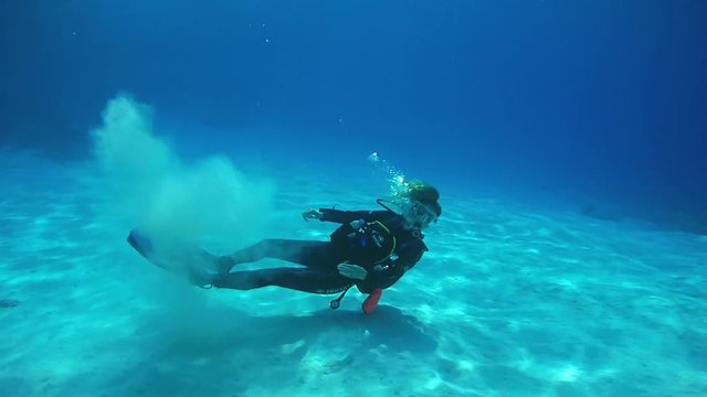  Young woman scuba diver plays with white sand on the bottom, Indian Ocean, Maldives
