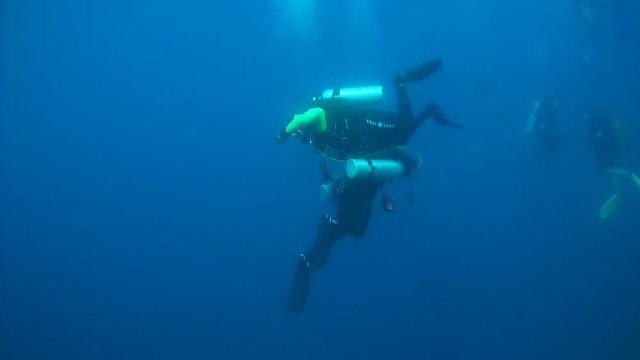 Scubadiver on his buddie's octopus hangs on the safety stop - Indian Ocean, Maldives
