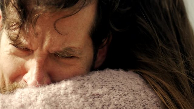 Sad man in love hugging girlfriend crying slow motion profile extreme closeup at sunset