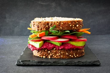 Draagtas Superfoodsandwich met bietenhummus, avocado, groenten en greens, op volkorenbrood tegen een leisteenachtergrond © Jenifoto