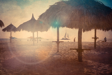 Grass hut tiki palapa on Aruba Caribbean beach with vintage texture and lens flare