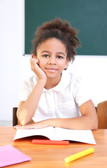 Portrait of beautiful African elementary schoolgirl sitting in classroom