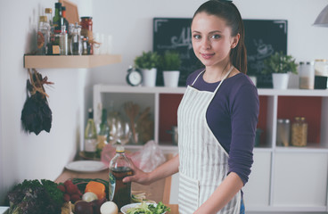 Young woman standing in her kitchen near desk