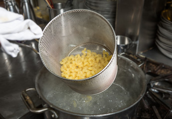 Removing cooked Macaroni pasta out of a pan of boiling water.