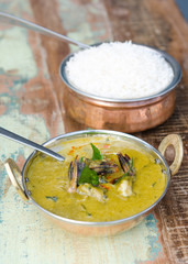 A delicious spicy prawn green curry, served with sticky rice in a rustic metal pan.