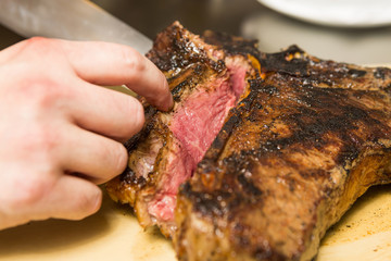 A knife slicing through a delicious grilledT Bone steak
