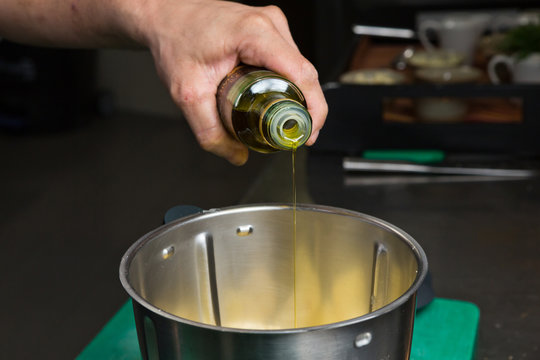 Extra virgin olive oil being poured into a metal mixing bowl.