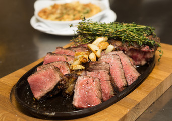 A selection of grilledT Bone steak pieces roasted garlic and rosemary, off the bone on a metal plate