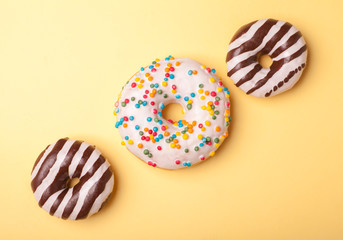 three tasty glazed donuts isolated on yellow background