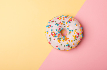 one tasty donut with white glaze isolated on pink-yellow background